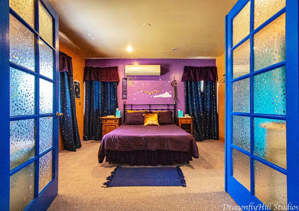 Main Bedroom featuring a queen sized bed, large TV, minisplit heat & AC, sound machine, blackout curtains, bathroom access expertly designed by DagonflyHill Studios